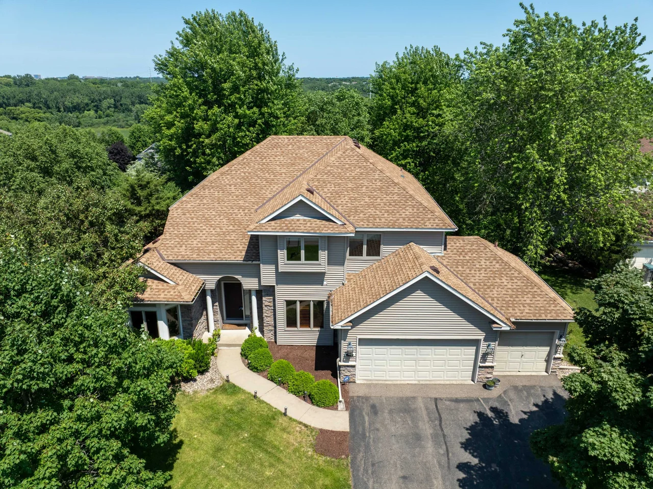 Elevated view of a home, driveway and tree-lined yard.