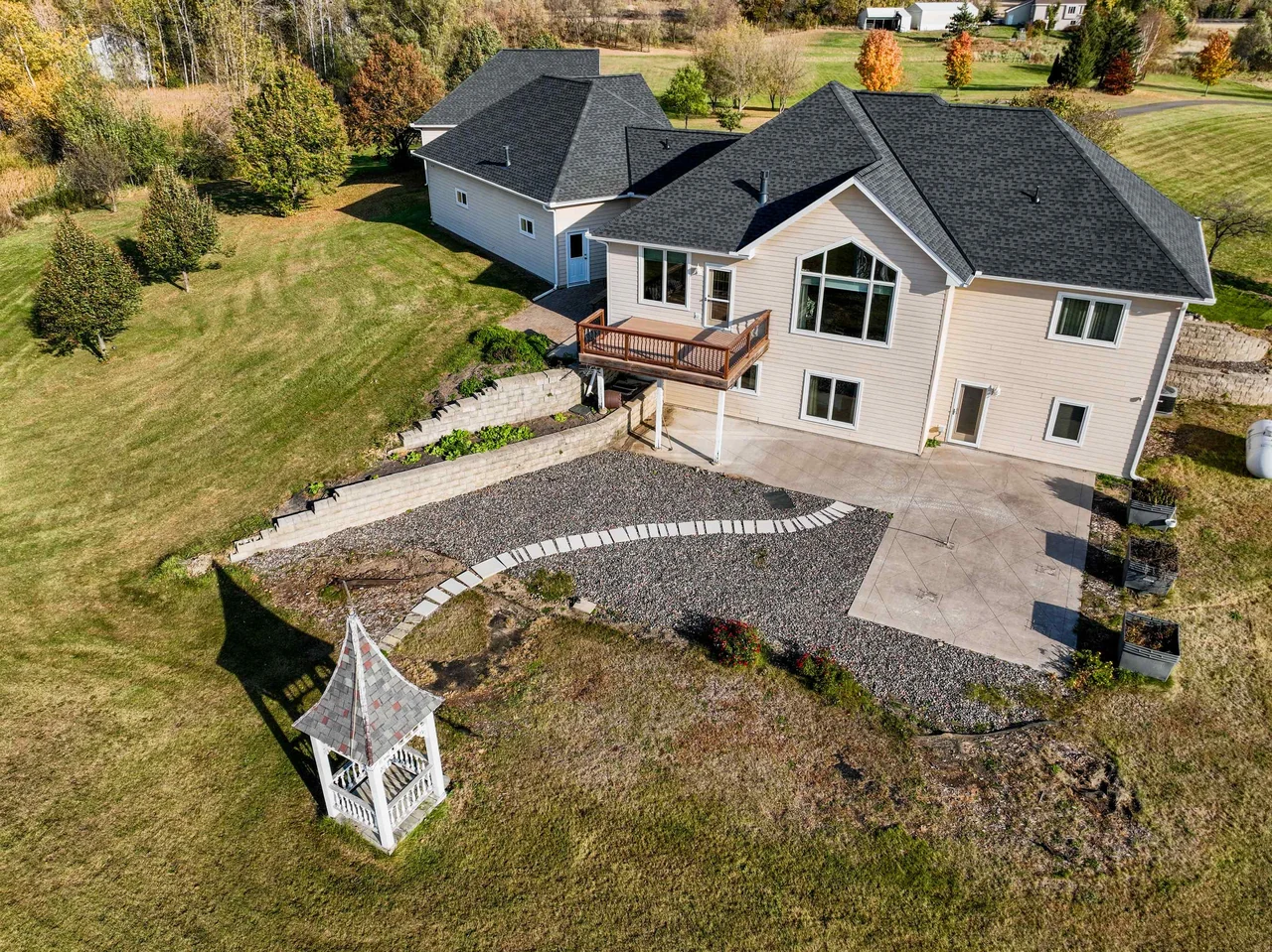 Elevated view of the rear of a house, patio, landscaped yard and gazebo.